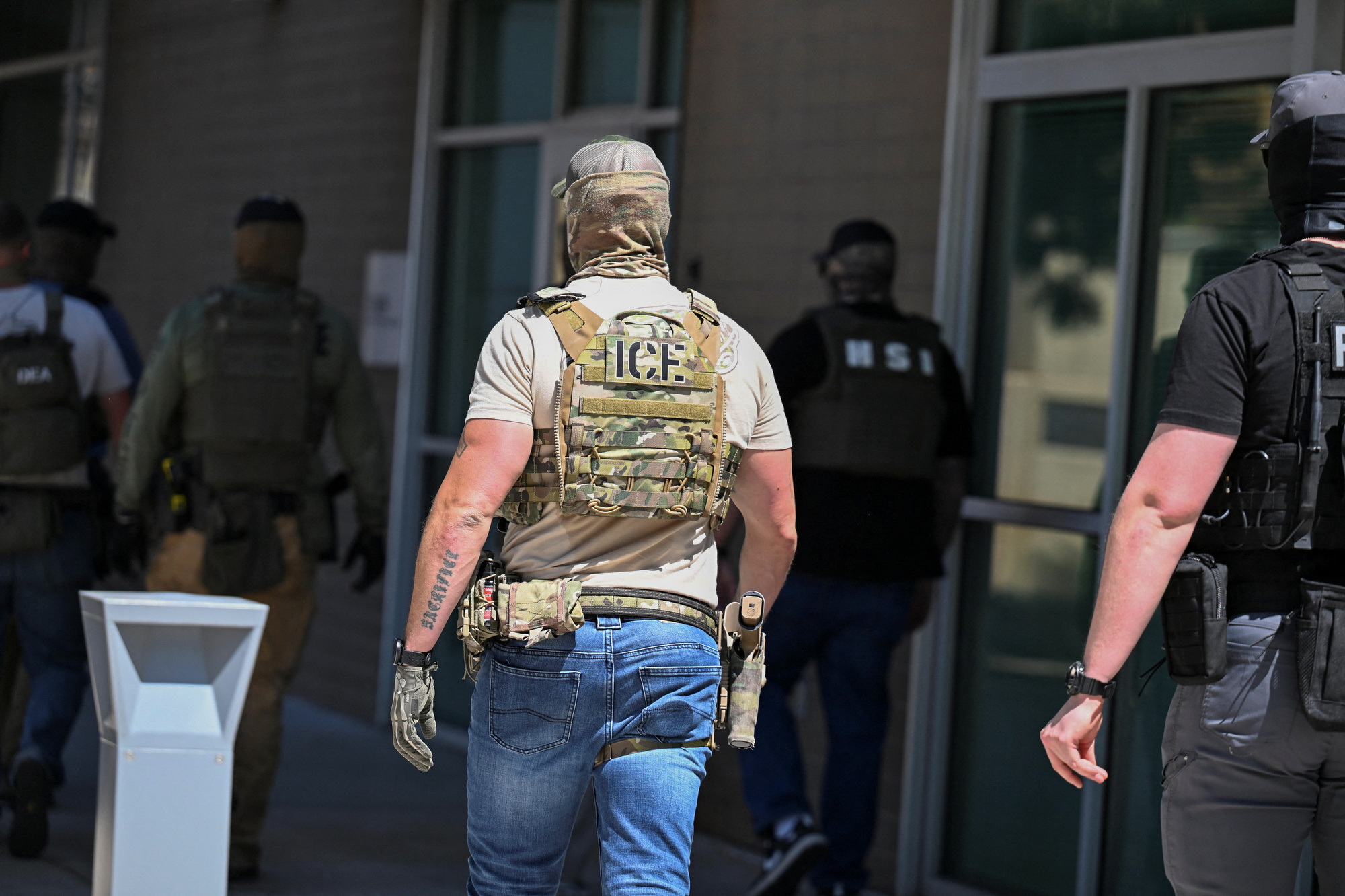 Law enforcement officers, including HSI and ICE agents, take people into custody at an immigration court in Phoenix