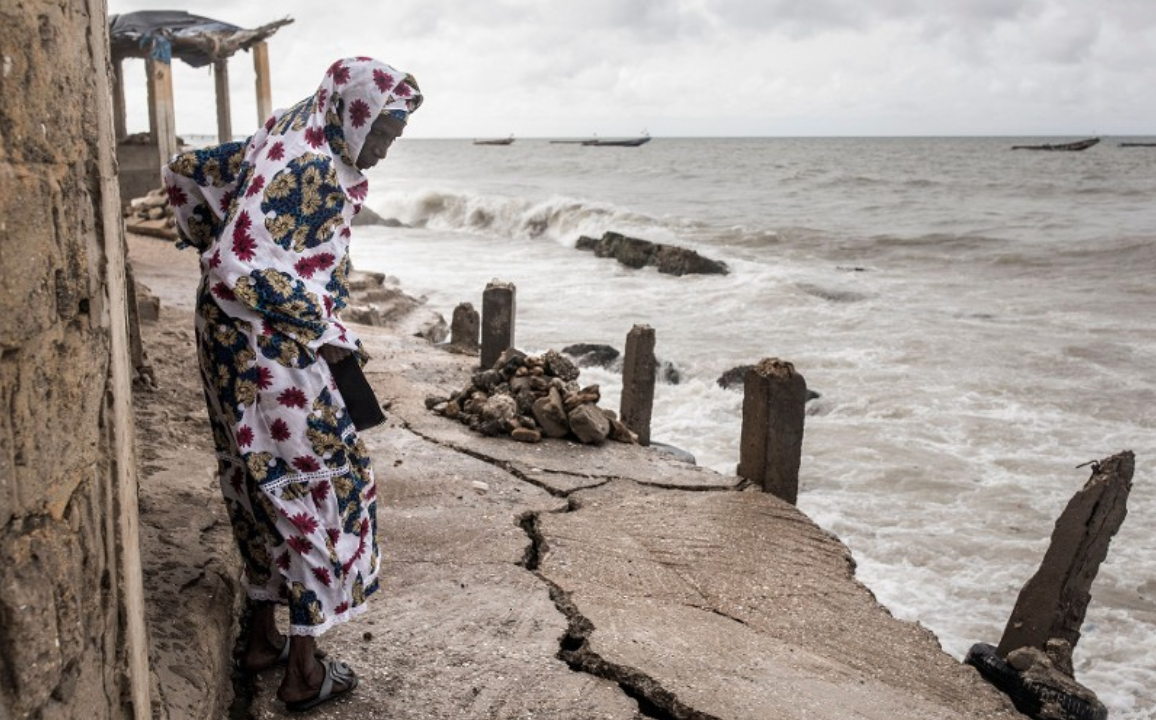 A woman looks down a newly formed crack in the walk way which leads to the Mosque in Bargny on September 18, 2020.