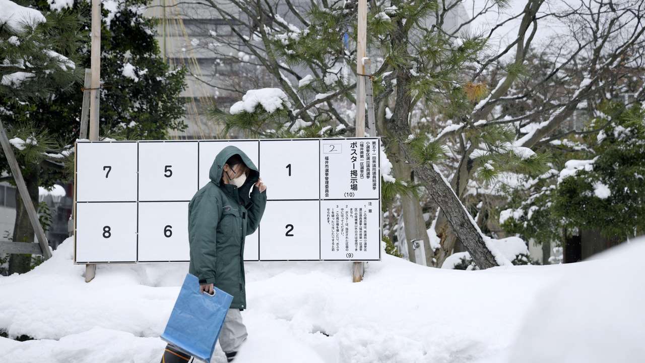A person walks past a bulletin board for posters of candidates for the February 8 snap election, where snow has accumulated, in Fukui