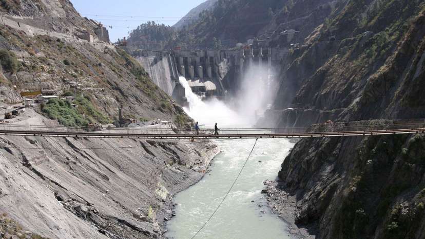 Labourers walk on a bridge near the newly inaugurated 450-megawatt hydropower project at Chanderkote