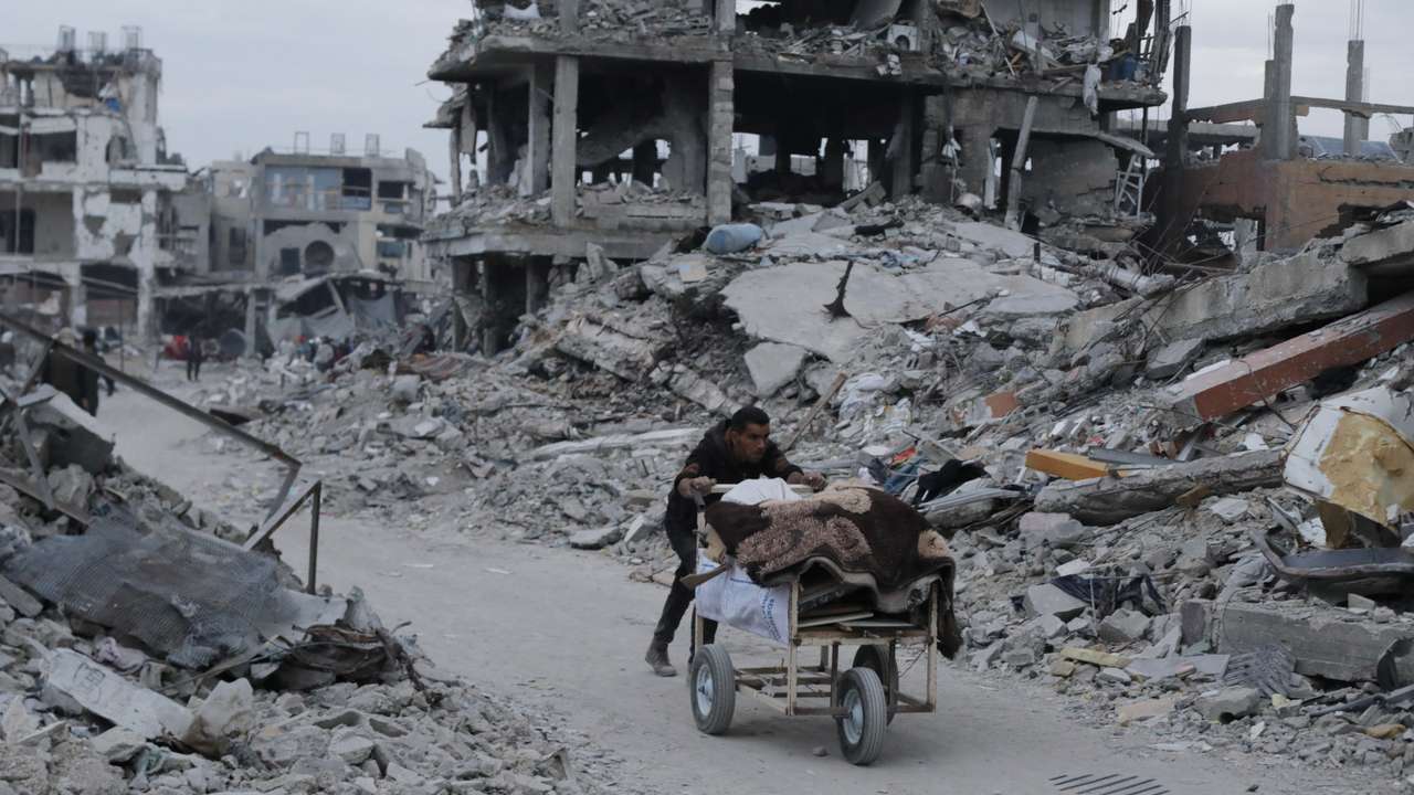 Palestinian pushes belongings past the rubble of buildings and houses destroyed during the Israeli offensive, amid a ceasefire between Israel and Hamas, in Jabalia
