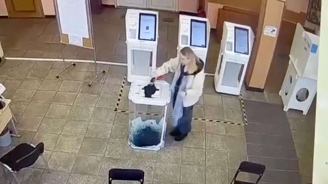 A woman pours a liquid into a ballot box, during the Russian presidential election in Moscow