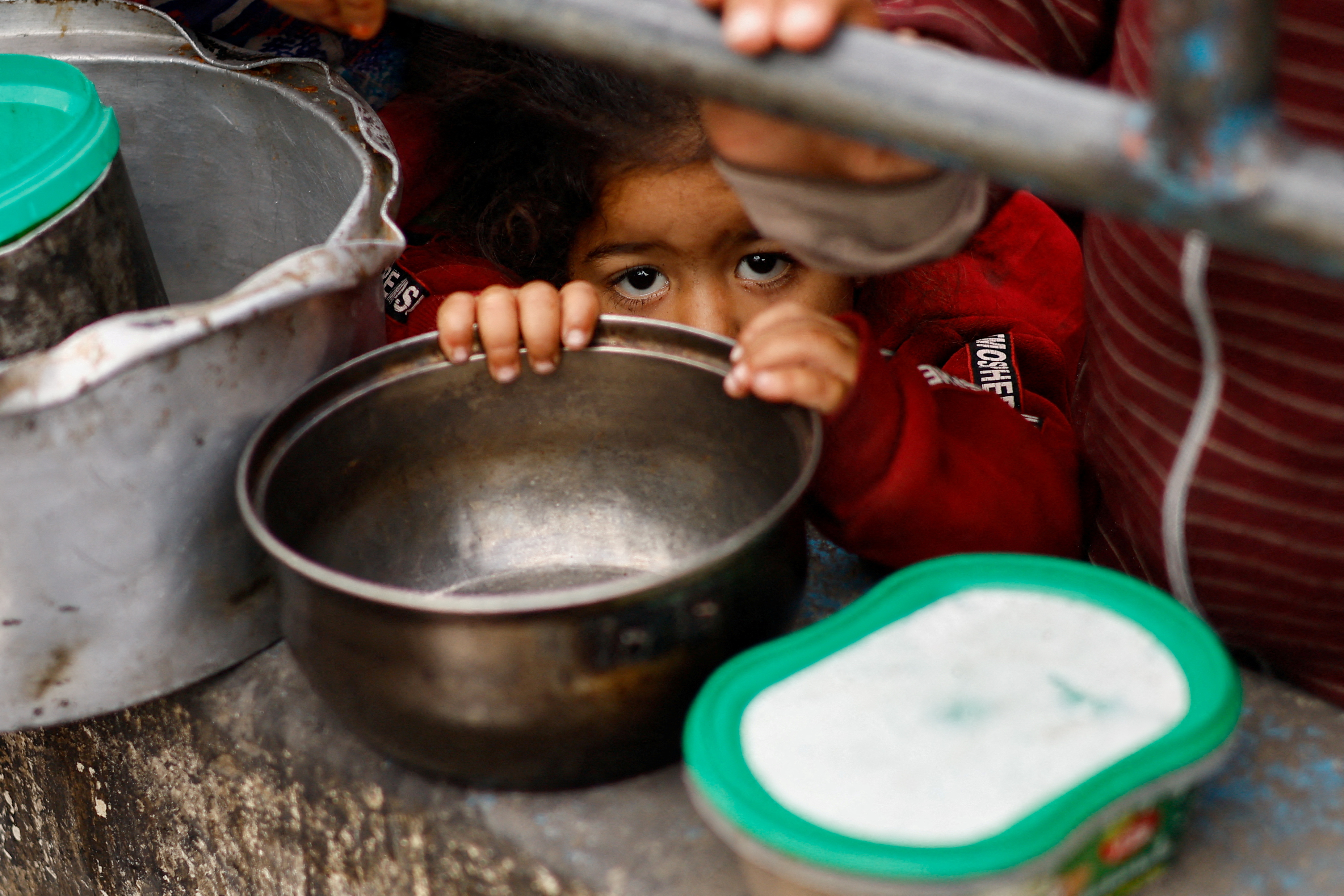 Palestinian children wait to receive food cooked by a charity kitchen amid shortages of food supplies, in Rafah