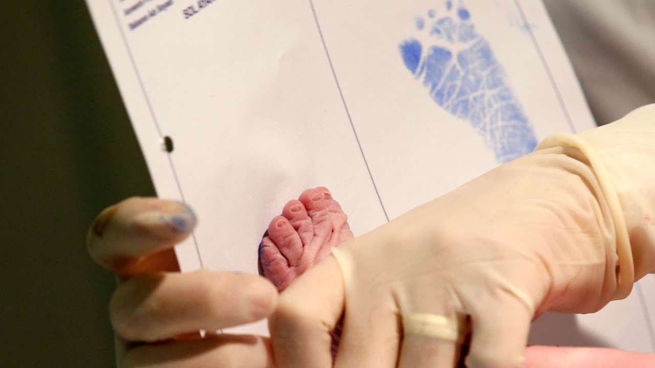 A doctor takes the footprint of a newborn baby for his birth certificate at a private clinic in Ankara