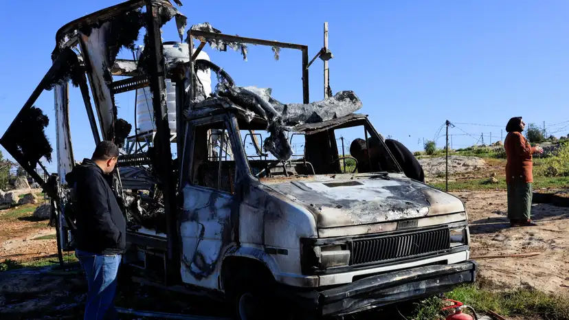 Palestinians check damage to a burned vehicle, in Susiya near Hebron