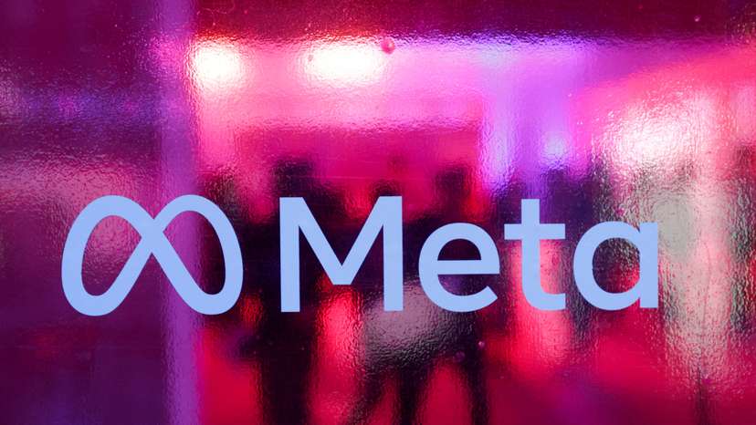 People walk behind a logo of Meta Platforms company, during a conference in Mumbai,