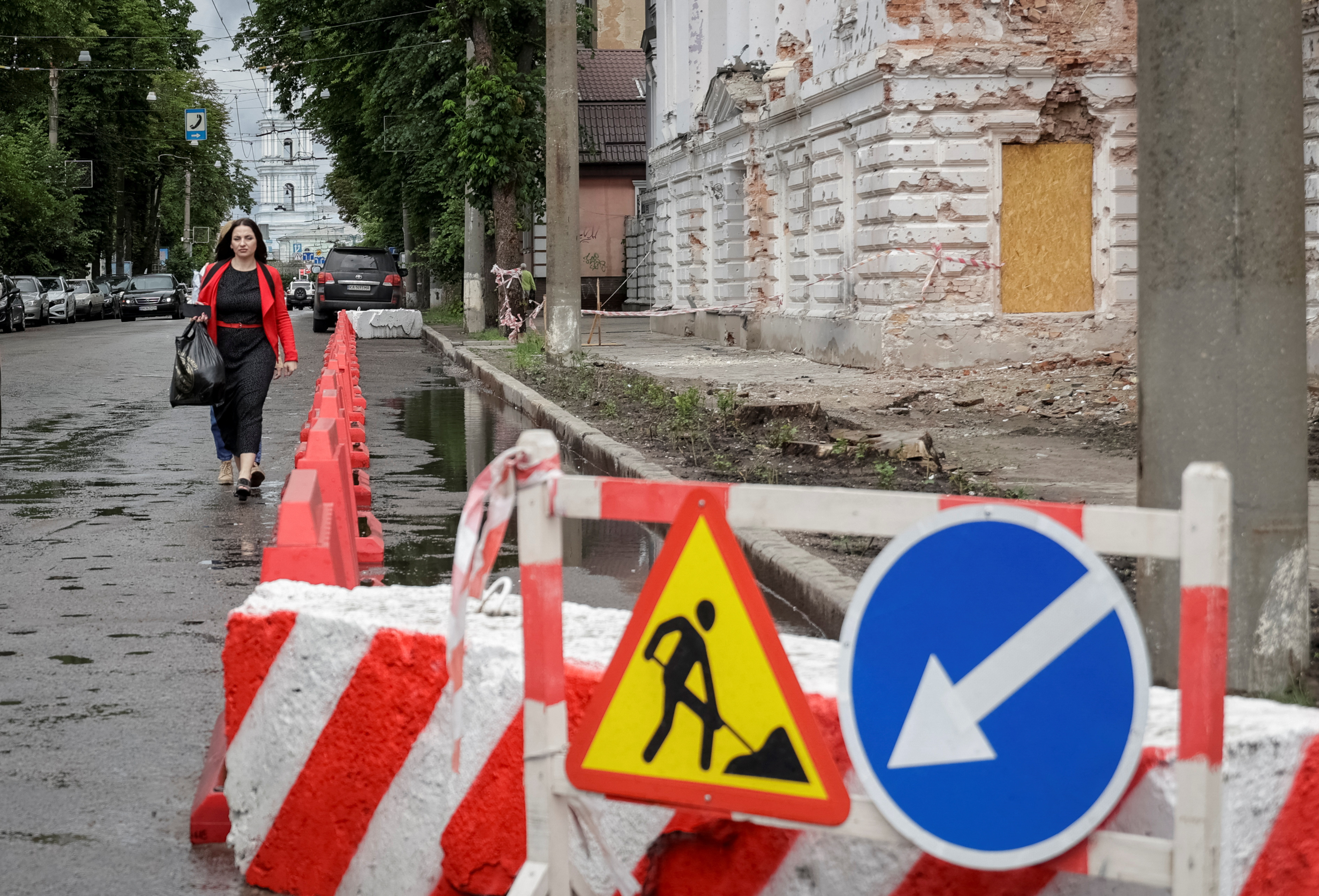 A resident walks at a street near a building damaged by Russian missile strikes in Sumy