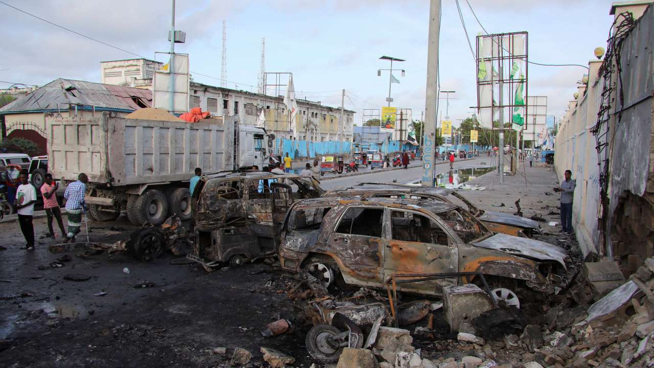 People gather near the wreckages of vehicles destroyed at the scene of an explosion outside a restaurant were patrons were watching the final of the Euro 2024 football tournament on TV, in Bondhere district of Mogadishu