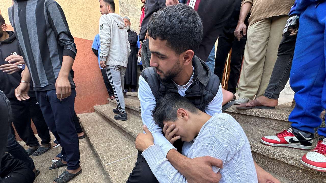 People mourn next to the body of a Palestinian killed in Israel strikes, at Nasser hospital in Khan Younis