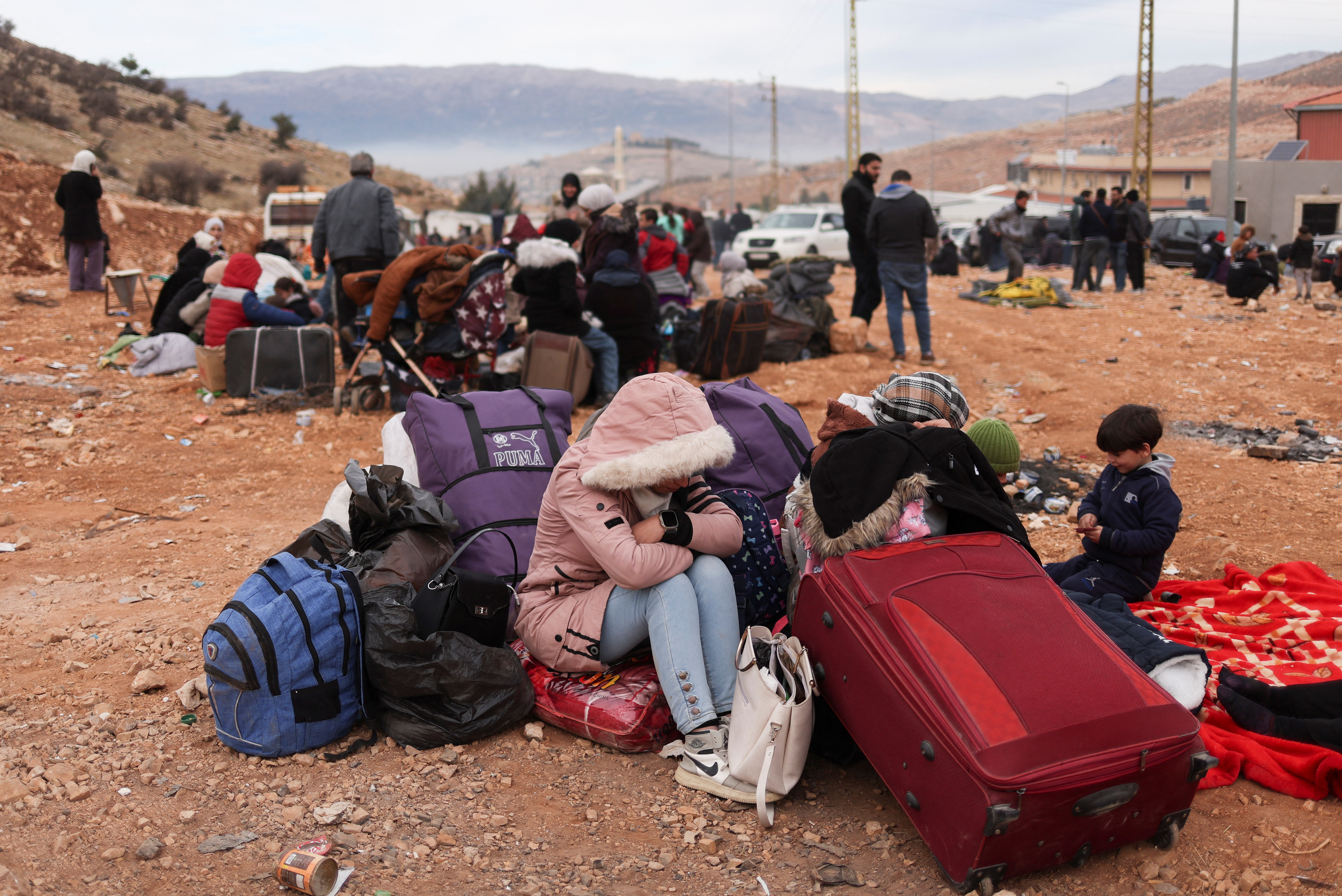People sit while waiting to cross the Lebanese border, at the Masnaa Border Crossing