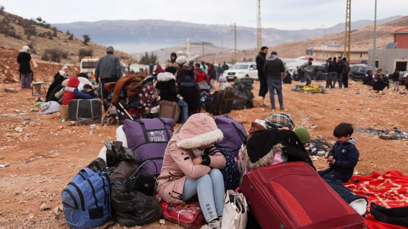 People sit while waiting to cross the Lebanese border, at the Masnaa Border Crossing