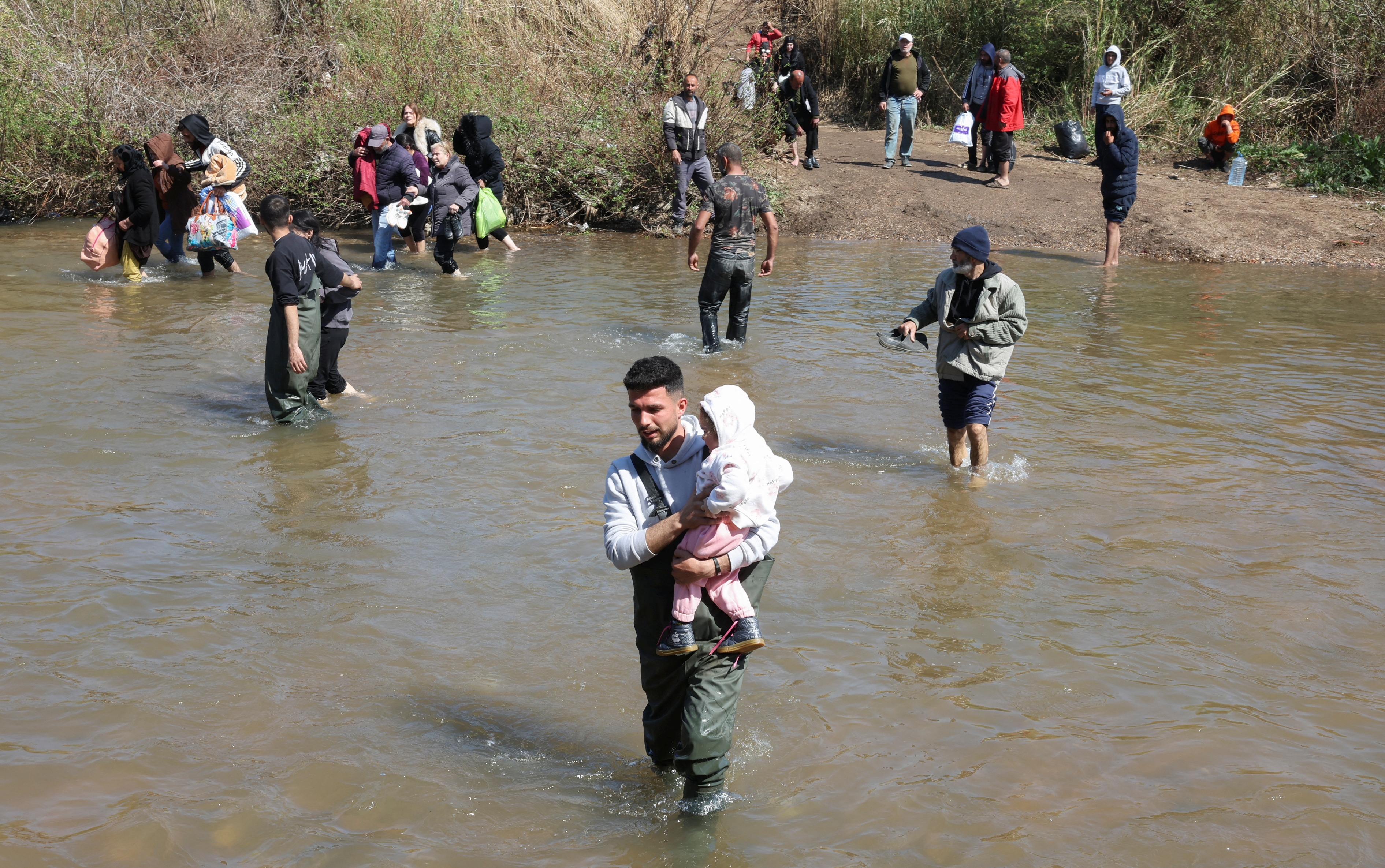 Alawite Syrians, who fled the violence in western Syria, walk in Nahr El Kabir River, in Akkar