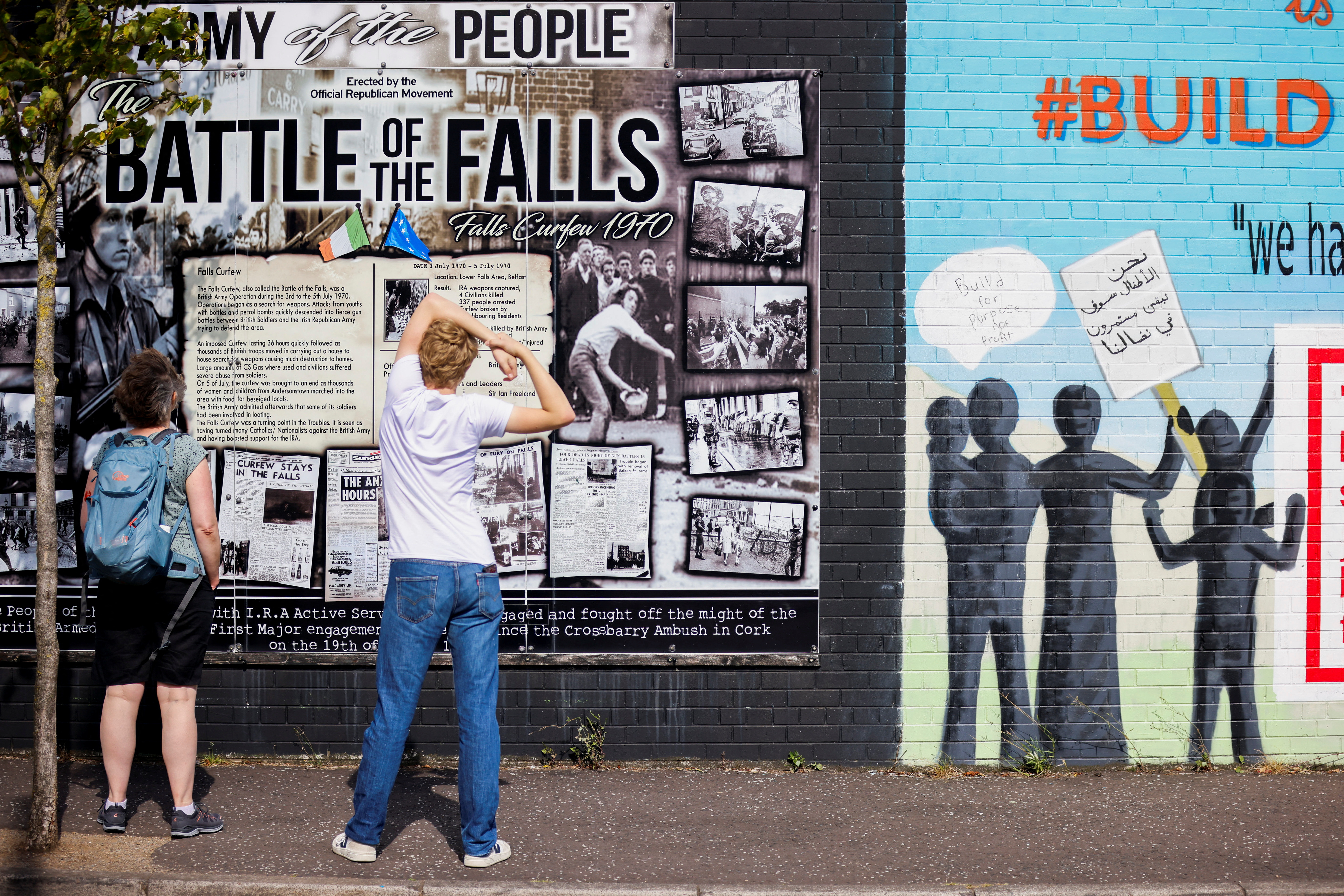FILE PHOTO: Persons look at a section of the Peace Wall in Belfast