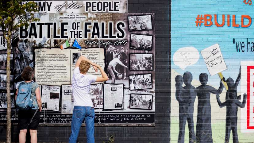 FILE PHOTO: Persons look at a section of the Peace Wall in Belfast