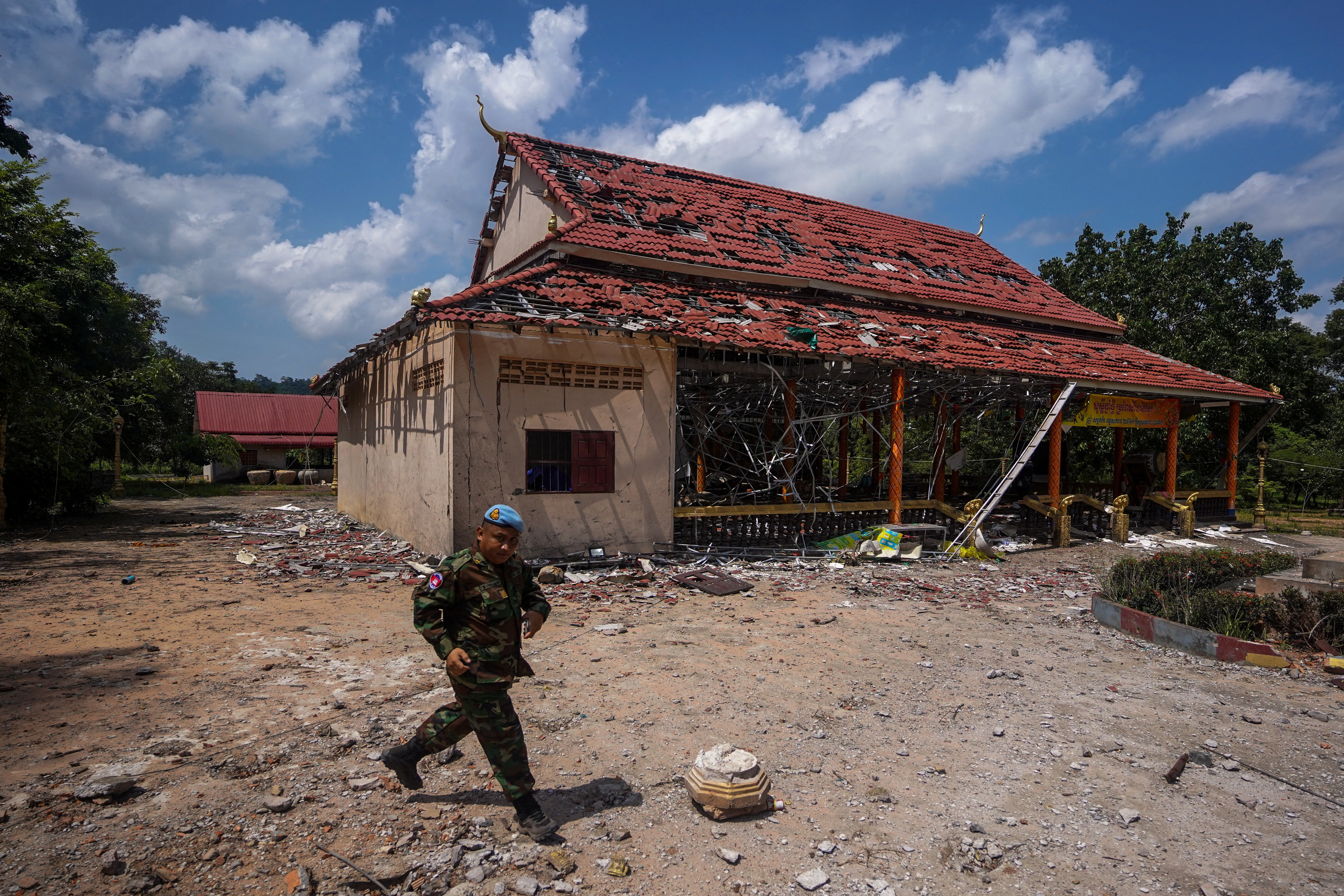 A Cambodian soldier walks past a damaged building during a visit of delegation of foreign diplomats to inspect a damaged area along the Thailand-Cambodia's border