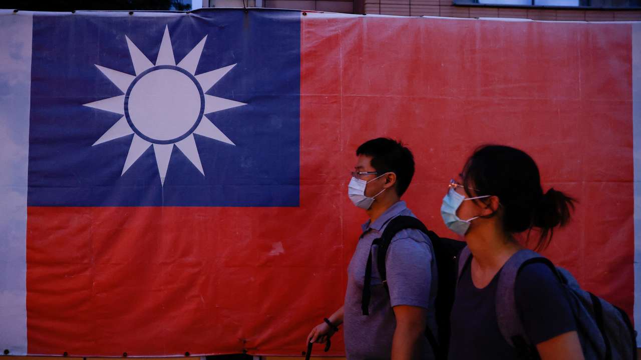 People walk past a Taiwan flag in Taipei