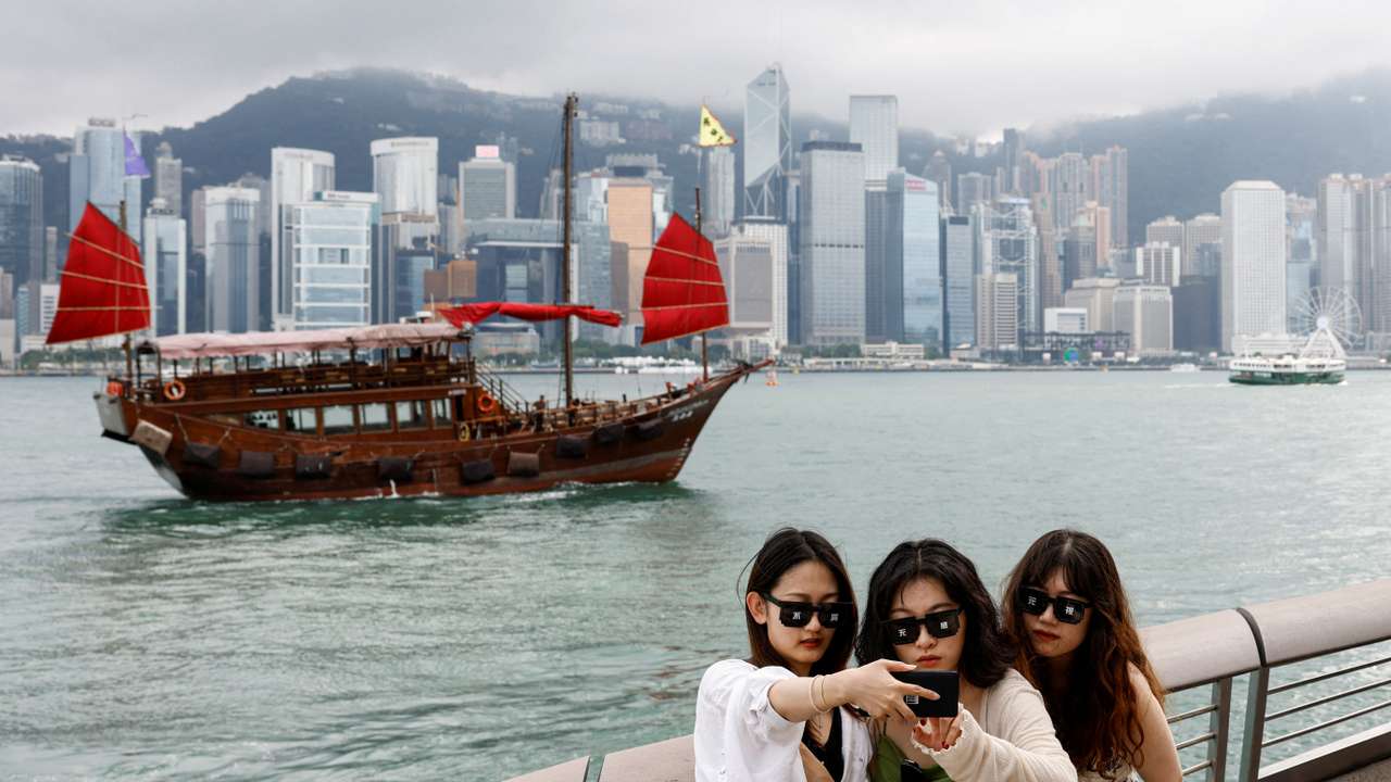 FILE PHOTO: Tourists take photos in front of Victoria Harbour, in Tsim Sha Tsui, in Hong Kong
