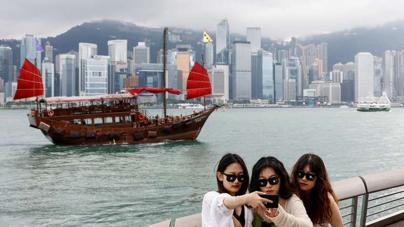 FILE PHOTO: Tourists take photos in front of Victoria Harbour, in Tsim Sha Tsui, in Hong Kong
