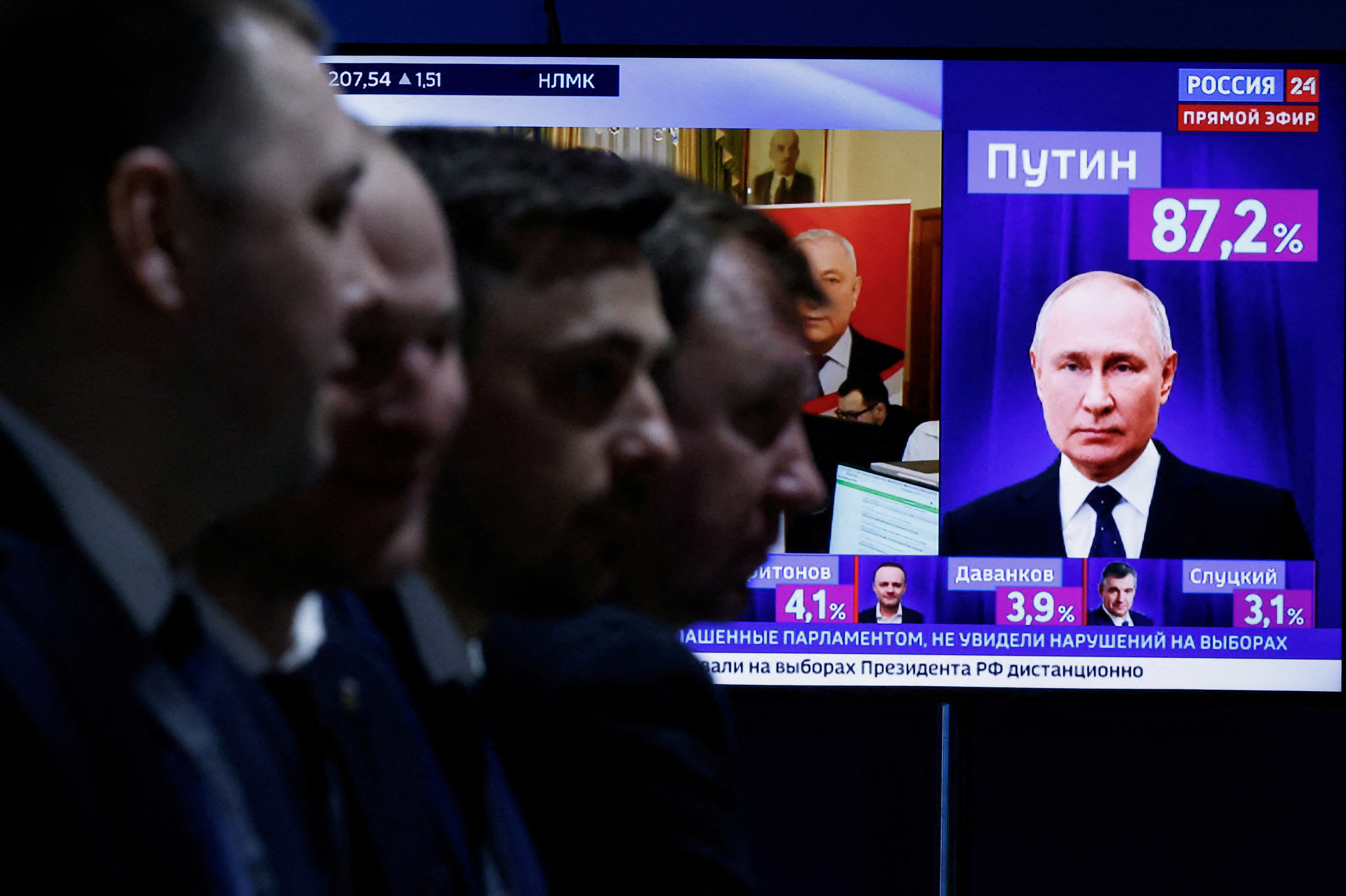 Men sit near a TV broadcasting news on the results of Russian incumbent President Putin, in Moscow
