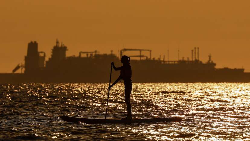A paddleboarder rows in front of an LNG carrier in Zelenogradsk