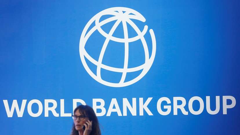 A participant stands near a logo of World Bank at the International Monetary Fund - World Bank Annual Meeting 2018 in Nusa Dua