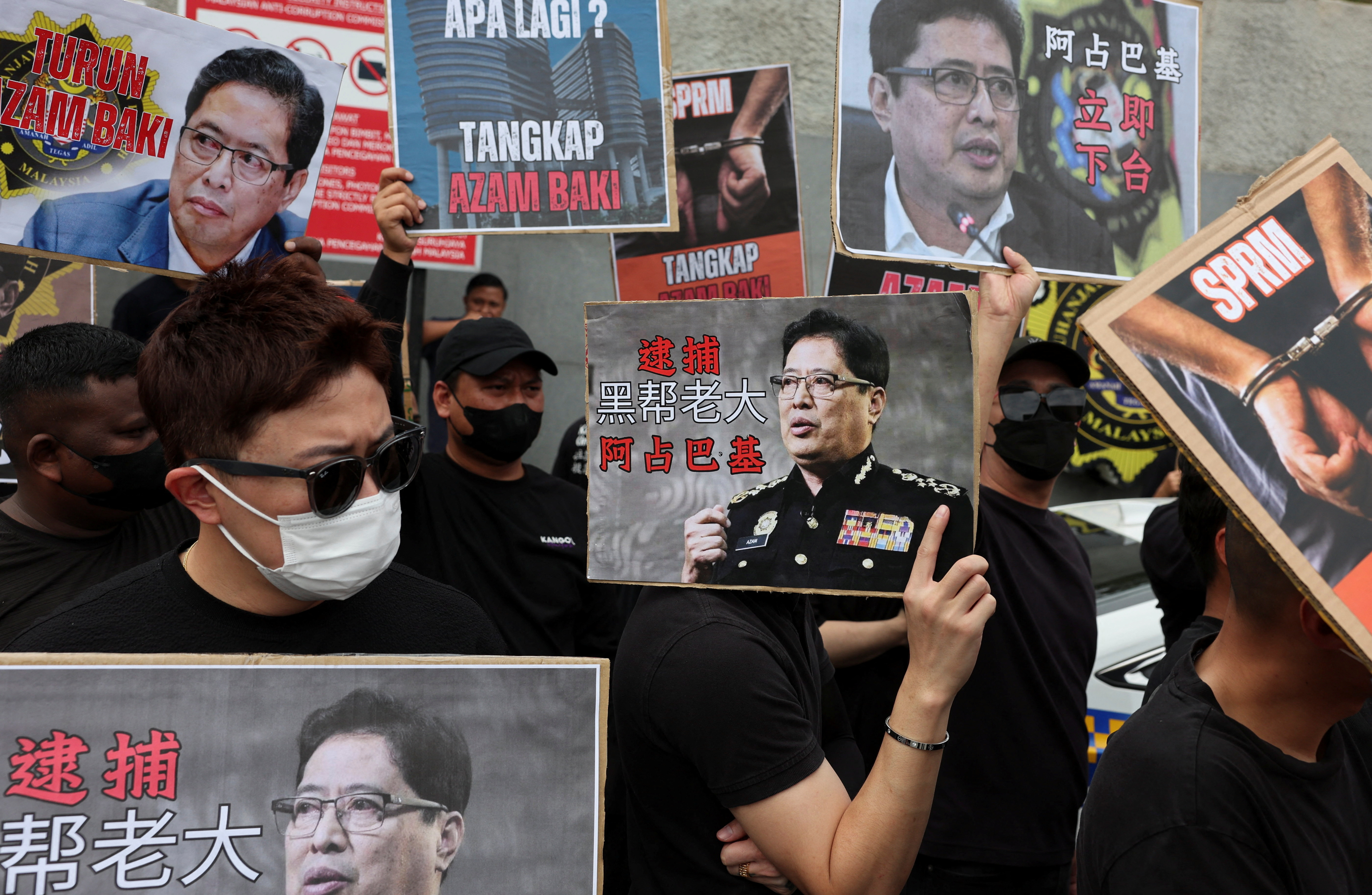 People hold placards bearing images of Azam Baki during a protest calling for his resignation at Putrajaya