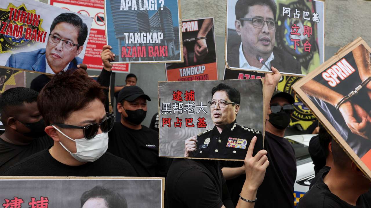 People hold placards bearing images of Azam Baki during a protest calling for his resignation at Putrajaya