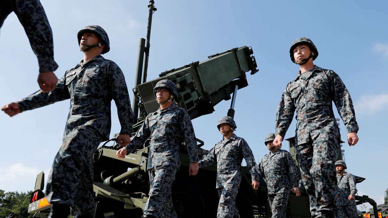 FILE PHOTO: Japan Self-Defense Forces (JSDF) soldiers walk past a Patriot Advanced Capability-3 (PAC-3) missile unit after Japan's Chief Cabinet Secretary Yoshihide Suga (L) reviews the unit at the Defense Ministry in Tokyo
