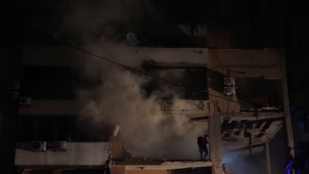 Smoke rises as a man stands on a damaged building at the site of an explosion, in what security sources say is an Israeli drone strike, in the Beirut suburb of Dahiyeh