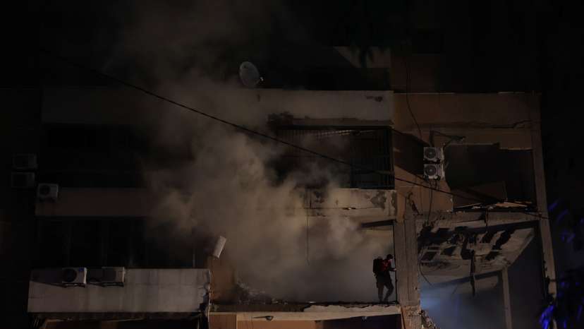 Smoke rises as a man stands on a damaged building at the site of an explosion, in what security sources say is an Israeli drone strike, in the Beirut suburb of Dahiyeh