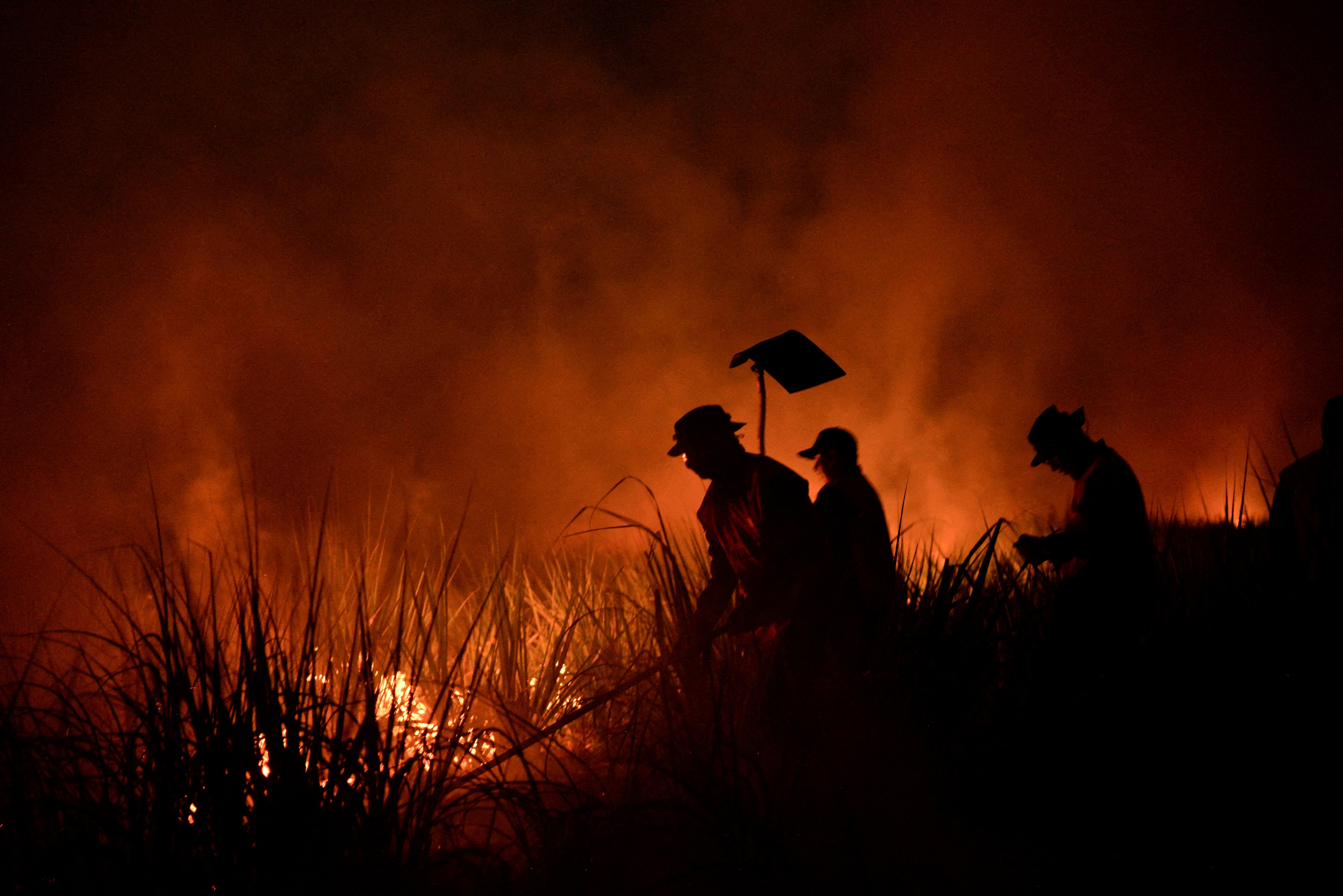FILE PHOTO: Firefighters tackle fire in a field as forest fires ravage the Bolivian Amazon, in San Buenaventura