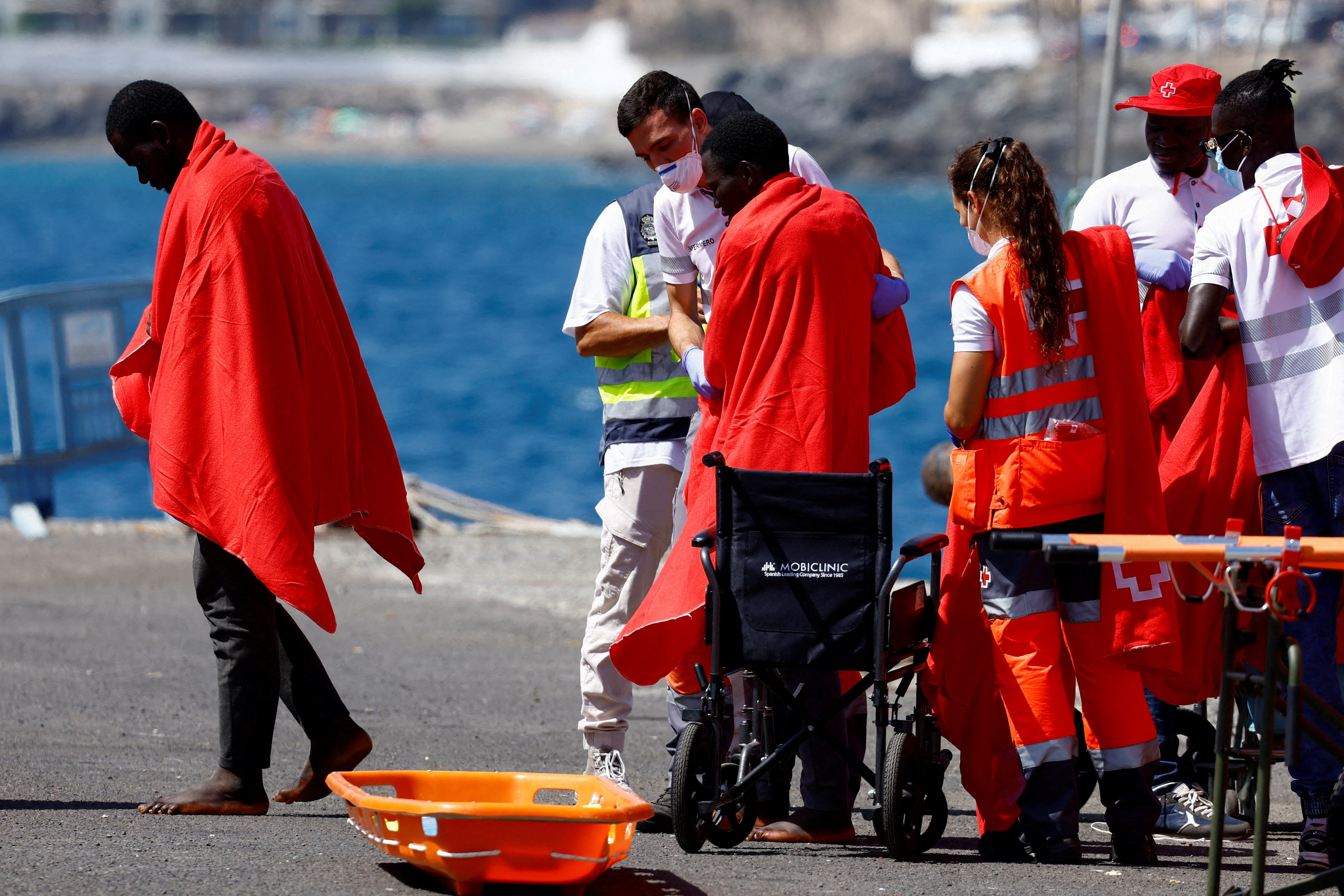 Migrants are treated by Red Cross volunteers after disembarking from a Spanish coast guard vessel at the port of Arguineguin, on the island of Gran Canaria