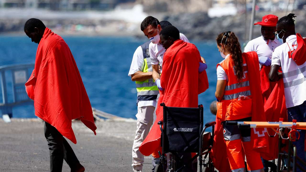 Migrants are treated by Red Cross volunteers after disembarking from a Spanish coast guard vessel at the port of Arguineguin, on the island of Gran Canaria