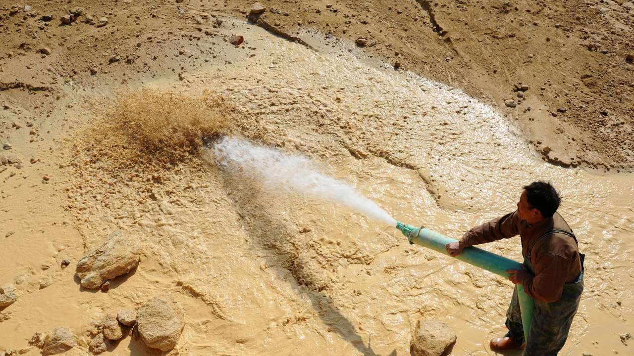 FILE PHOTO: A worker waters the site of a rare earth metals mine at Nancheng county