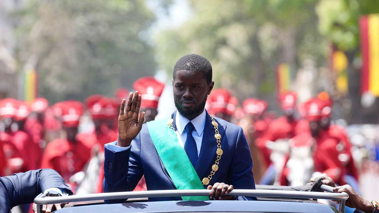 Senegal's newly-elected President Bassirou Diomaye Faye waves to supporters from a car after taking an oath of office as president during the inauguration ceremony in Dakar