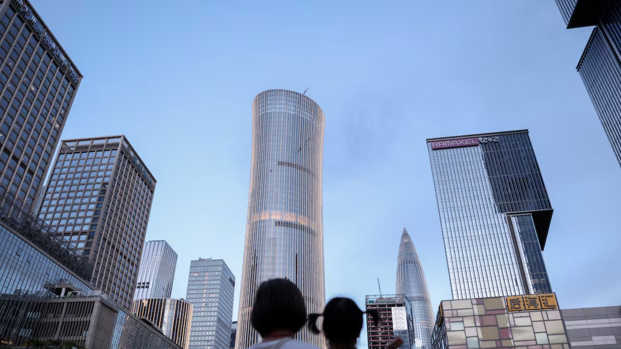 A woman holds a child near office buildings in Shenzhen, Guangdong province, China September 15, 2025. REUTERS/Tingshu Wang/File Pho