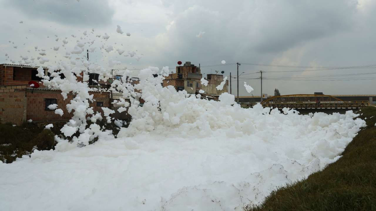 Pollutant foam generated by a river full of waste is blown by the wind next to houses, in Mosquera