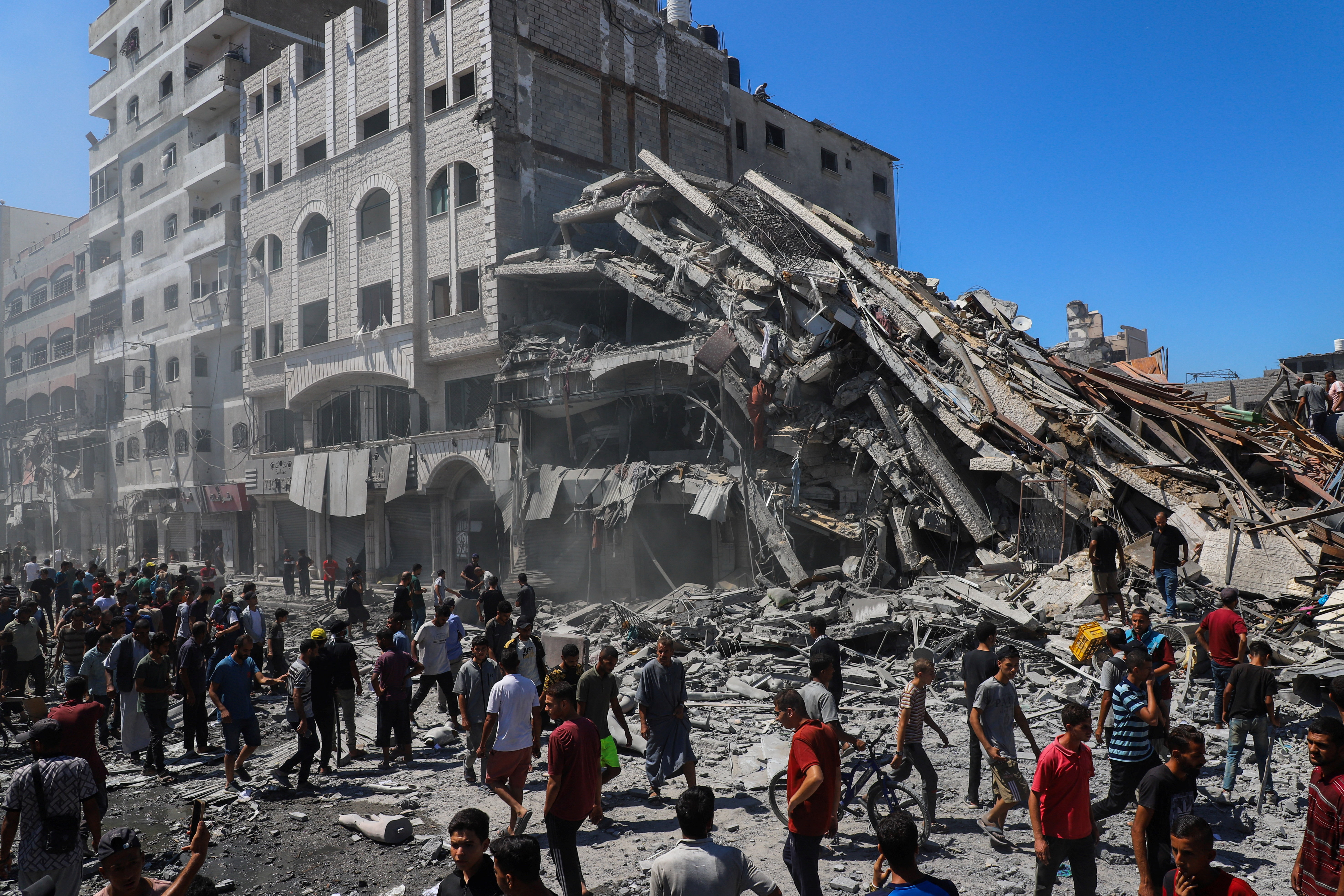 Palestinians inspect the site of an evacuated house, after it was hit by an Israeli air strike, in Gaza City