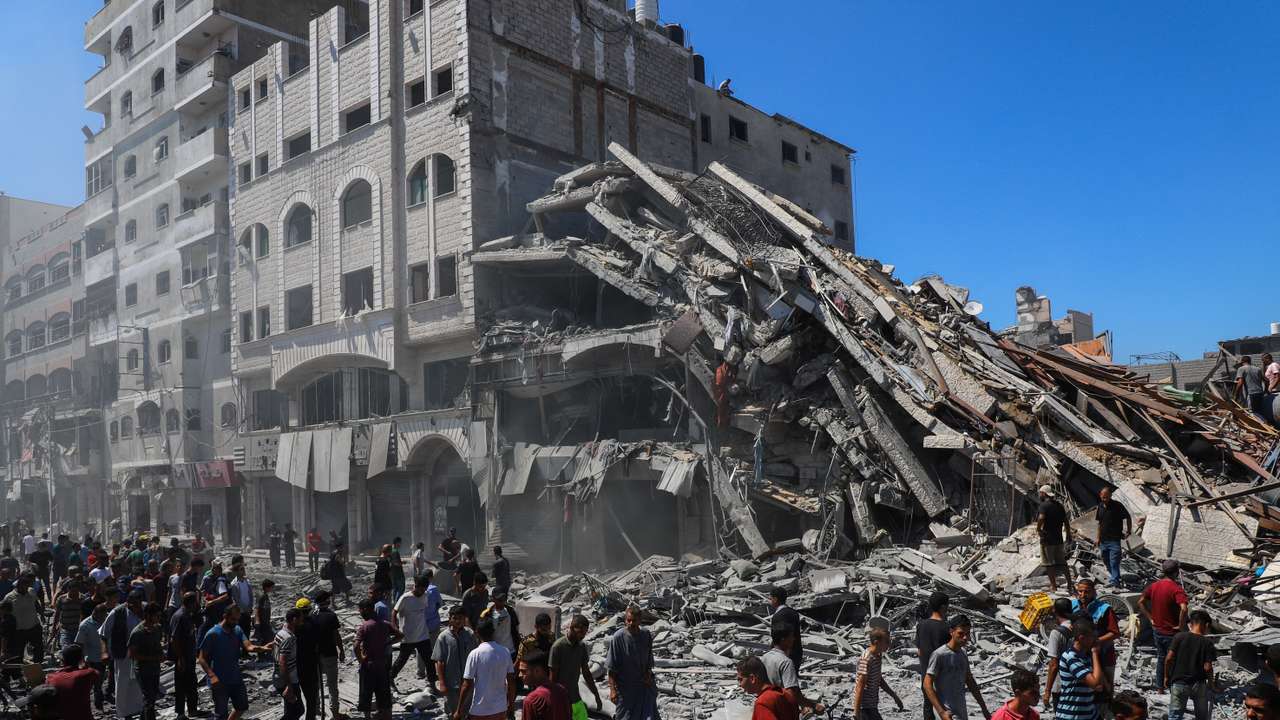 Palestinians inspect the site of an evacuated house, after it was hit by an Israeli air strike, in Gaza City