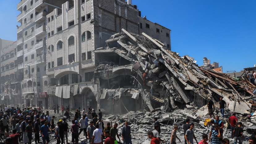 Palestinians inspect the site of an evacuated house, after it was hit by an Israeli air strike, in Gaza City