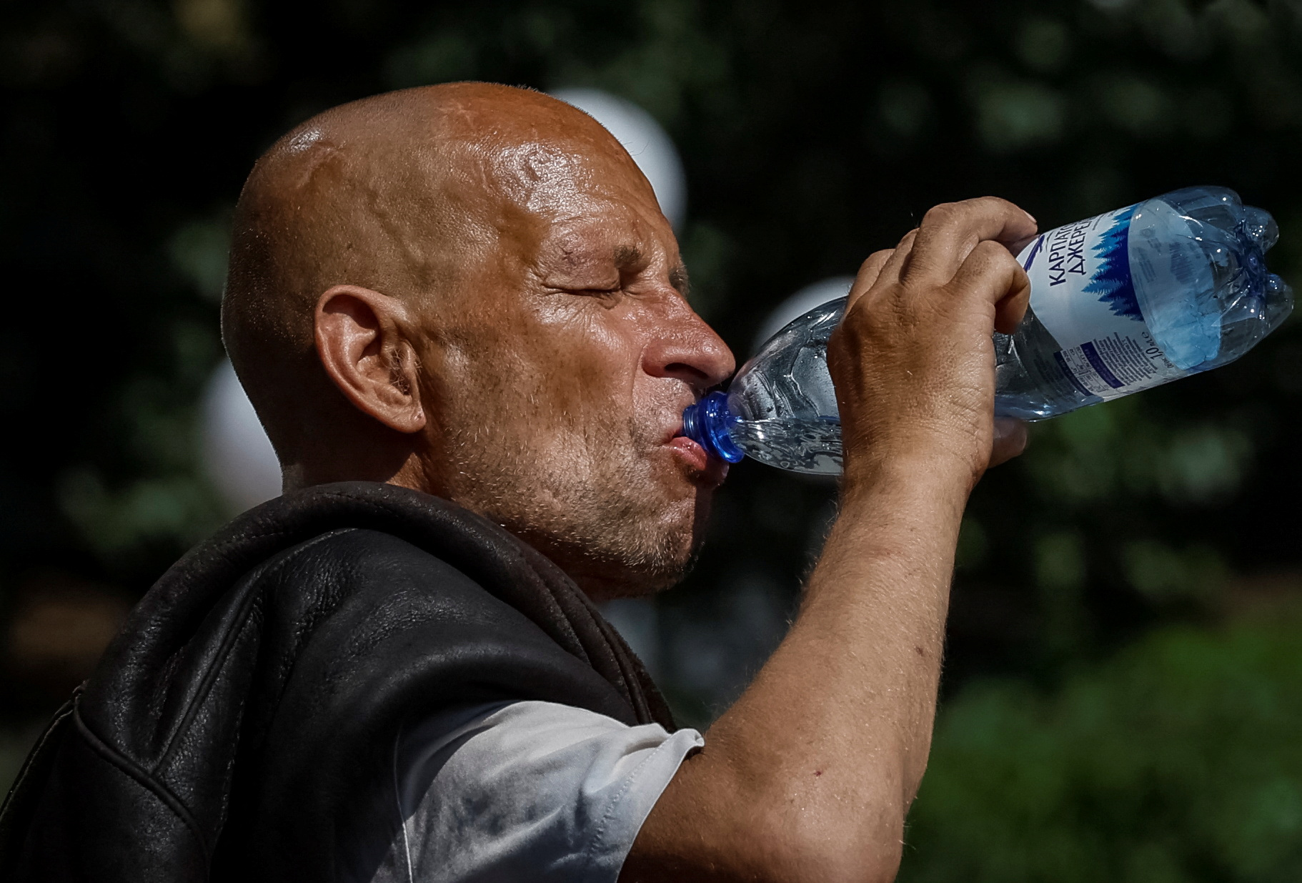 A man drinks water on the street during an abnormally hot summer day in central Kyiv