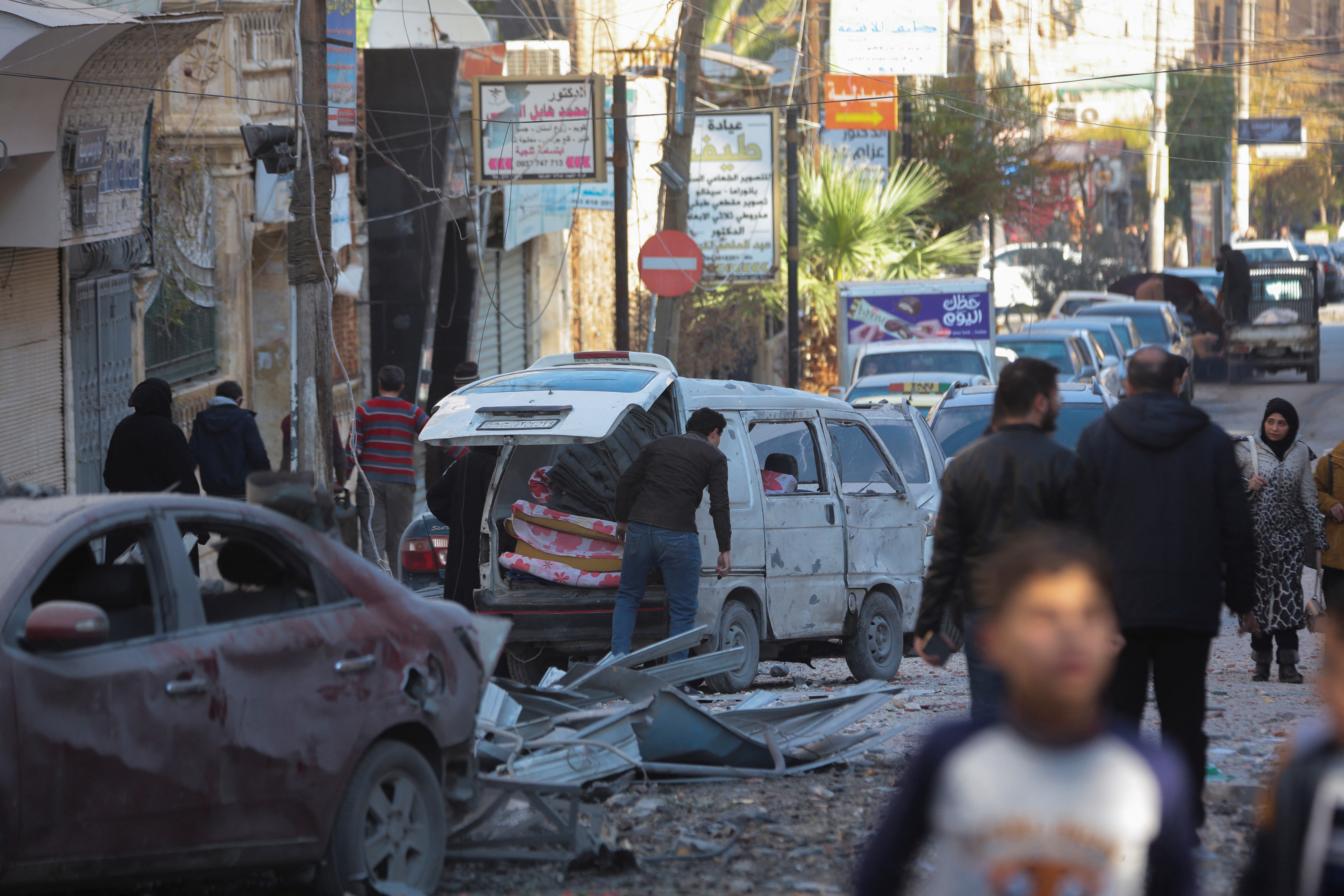People walk past a damaged site in Aleppo