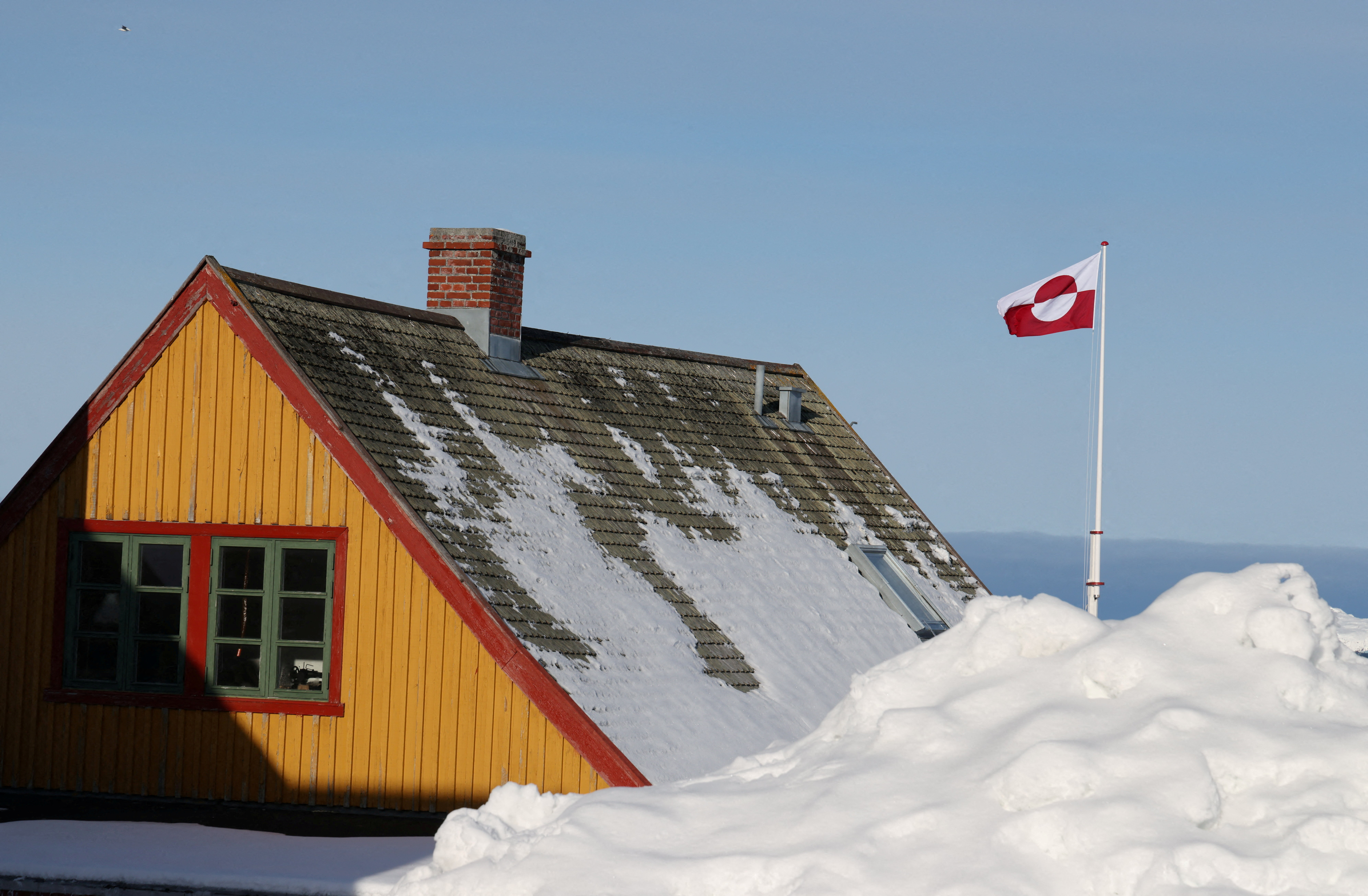 Greenland's national flag flutters next to a house in Nuuk
