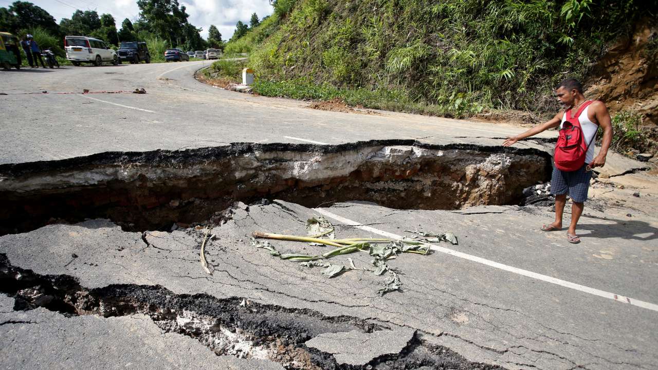 A man gestures next a section of the NH 8 that was damaged by heavy rains in Khowai district