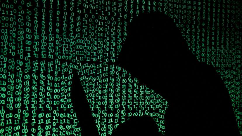FILE PHOTO: Hooded man holds laptop computer as cyber code is projected on him in this illustration picture