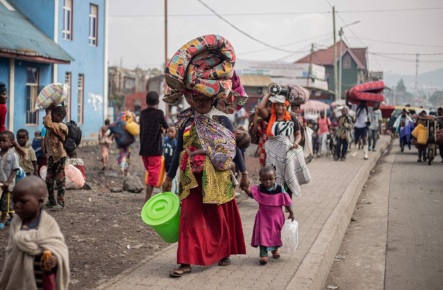 A woman carries a mattress and other belongings on her head as she flees from Kibati, where fighting has intensified, towards the city of Goma