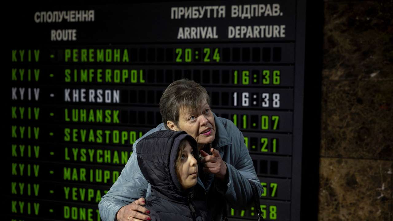A woman and a child check departure times in the hall of the main train station in Kyiv