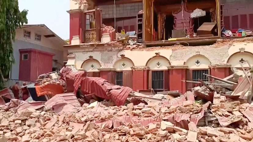 People stand near a collapsed temple following an earthquake in Mandalay