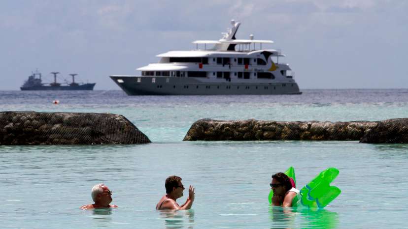 Tourists enjoy the sea as a safari boat sails past, near Vihamanafushi island