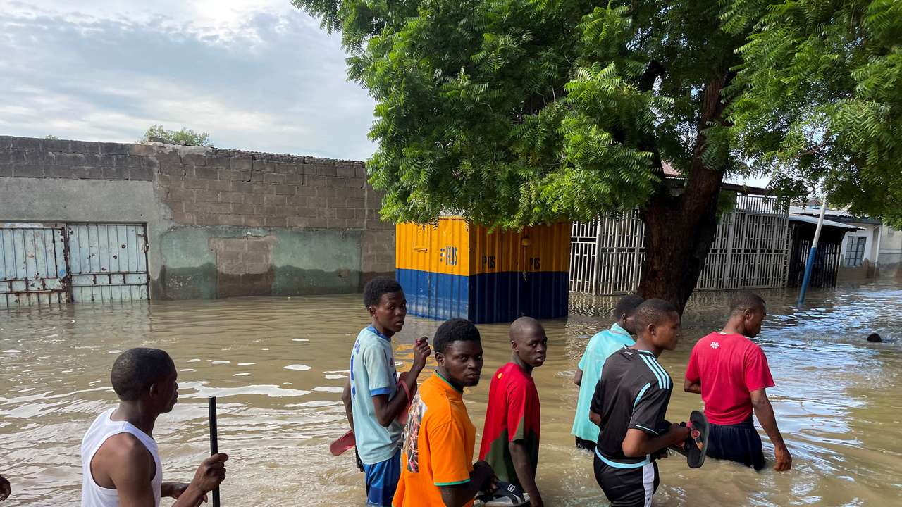 FILE PHOTO: Residents walk in a flooded area during rescue operations in Maiduguri